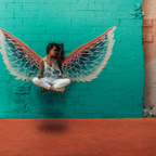 Woman posing in front of vibrant mural with angel wings in downtown Toronto.