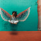 Woman posing in front of vibrant mural with angel wings in downtown Toronto.